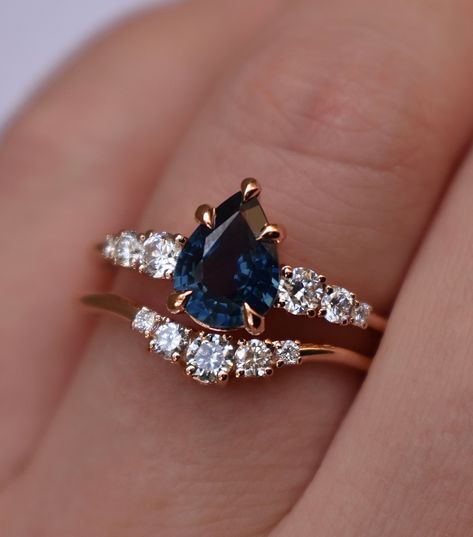 Charming teal blue sapphire engagement ring set radiates beauty from every angle. An exquisite central pear shaped teal sapphire is enchanted by lustrous diamonds. The dazzling array of gems are meticulously encased in a rose gold base for a classically feminine feel. This unique engagement ring set combines an old world elegance with modern glamour. Just perfect for brides, seeking a ring that truly stands out from the crowd. Sapphire Engagement Ring Set Details: Central Stone: Natural teal blu Sapphire Engagement Ring Pear, Pear Sapphire Ring, Unique Engagement Rings Sapphire, Sapphire Wedding Ring Set, Blue Green Sapphire Ring, Sapphire And Diamond Engagement Ring, Rings Sapphire, Sapphire Engagement Ring Set, Pretty Engagement Rings