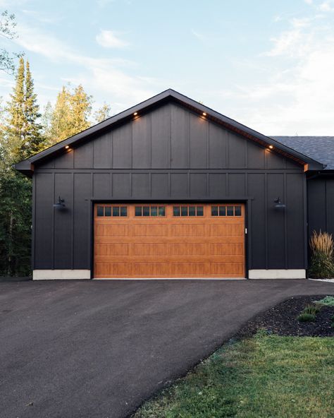 Benjamin Moore Black Siding Benjamin Moore Onyx with wood grain finish steel garage door #BenjaminMooreBlack #BlackSiding #BenjaminMooreOnyx #woodgraingaragedoor #steelgaragedoor #garagedoor Black And Galvanized Exterior, Black House With Black Garage Door, All Black Exterior House With Wood, Black House Brown Garage Door, Cedar House Black Trim, Black Steel Siding, Black Steel Siding Exterior House, Black Steel House Exterior, Homes With Black Siding