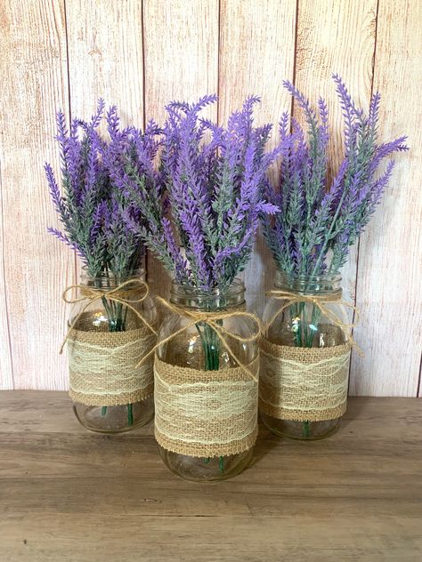 "These Mason Jars with Lavender Bouquets are perfect for weddings, baby showers and bridal showers. These jars are also a great addition to your home decor, use as centerpieces or simple table decor.  Mason Jars are Ball Regular Mouth Quart Size Jars with twine attached at the top. Each jar will have two faux lavender stems.  A burlap and lace mason jar sleeve will be included for each jar.  Lavender Bouquet is approximately 14\" Tall.  Click my shop link below if you are interested in more styl Lavender Wedding Centerpieces, Mason Jar Sleeve, Backyard Wedding Favors, Simple Table Decor, Rustic Chic Wedding Decor, Jar Centerpiece Wedding, Lavender Bouquets, Lace Mason Jars, Lavender Wedding Flowers