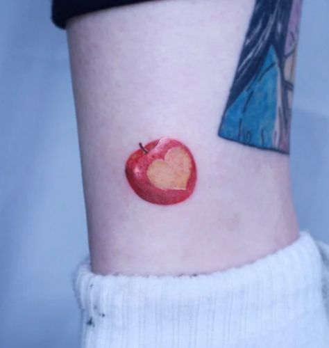 The apple, everyone's favorite fruit, is designed with red ink in this tattoo. Make a heart on one side of the apple tattoo to express your affection for the apple fruit. This tattoo is appropriate for males and females and... Mini Apple Tattoo, Apple Heart Tattoo, Apple Of My Eye Tattoo, Bitten Apple Tattoo, Apple Pie Tattoo, Fruit Bowl Tattoo, Apple Core Tattoo, Apple Tattoo Design, Fiona Apple Tattoo