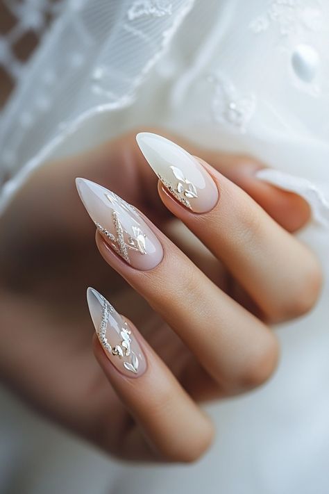 Hand with elegant, almond-shaped nails featuring a delicate, white floral design. Bride Nails With Rhinestones, Nails Design For Bride, Cute Wedding Nails The Bride, Rustic Wedding Nails For Bride, Almond Nail French Design, Wedding Nail Designs For Bride, Unique Bridal Nails, Bride's Nails Wedding, Wedding Nails For Bride Classy Bridal