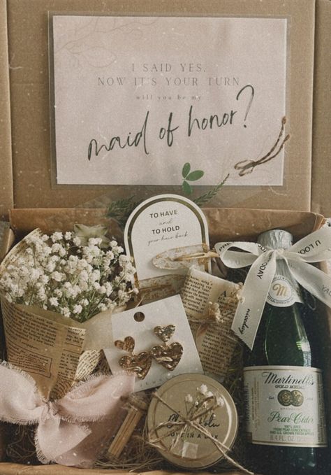 Our MOH proposal box is thoughtfully curated with the following items: (H)= Handmade - Petite bouquet of Baby Breath (H) - Double Golden Heart Earrings - Hair Clips - Goat Milk Soap (H) - Martinelli's Gold Medal Sparkling Cinder (H) - Floral Bookmark - Soy Wax Candle (H) -  Safety matches The gift can be shipped directly to the MOH by updating the name and address during checkout. Make sure to mark the order as "a gift" and leave a note saying who it is from. Notably, our candles and soaps are diligently cured before being made available for purchase. While we understand that orders may be placed swiftly, we feel it's essential to disclose that our candles and soaps typically undergo a two-week curing process. This process involves the gradual hardening of soy wax to ensure an even dispers Ideas To Ask Maid Of Honor Gift Boxes, Maid Of Honor Gift Basket, Maid Of Honor Proposal Unique, Maid Of Honor Proposal Best Friend, Simple Will You Be My Bridesmaid, Personal Bridesmaid Proposal, Bridesmaid Proposal Garden Theme, Emerald Green Bridesmaid Boxes, Simple Bridal Party Proposal