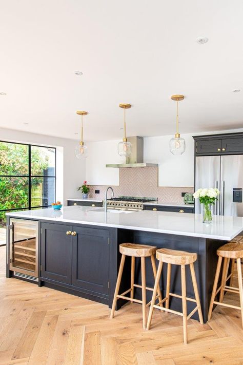 This lovely kitchen extension in Bromley features a large kitchen island separating the dinning area from the main kitchen dressed with brass knobs. A large range cooker sits beneath the stunning herringbone patterned, pink, tiled splashback! #herringbonekitchens #herringbonepantry #bespokekitchensforlivingin #bespokekitchens #blackkitchen #kitchenisland #pinktiles #brasshandles #brasshardware #quartzworktops Kitchen With An Island, Kitchen Diner Extension, Open Plan Kitchen Dining Living, Open Plan Kitchen Diner, Open Plan Kitchen Dining, Open Plan Kitchen Living Room, Kitchen Dining Living, Kitchen Room Design, Kitchen Inspiration Design