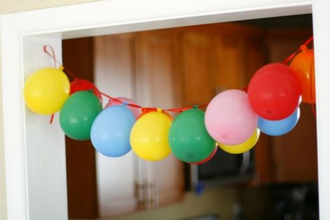 To create a hanging balloon garland- blow up all your balloons with a hand pump and thread a needle with clear fishing wire or ribbon through the knotted tab of each balloon- as seen here. Ballon Banner, Hanging Balloons, Rainbow Birthday Party, Rainbow Balloons, Carnival Birthday, Balloon Banner, Rainbow Birthday, Birthday Fun, Party Balloons