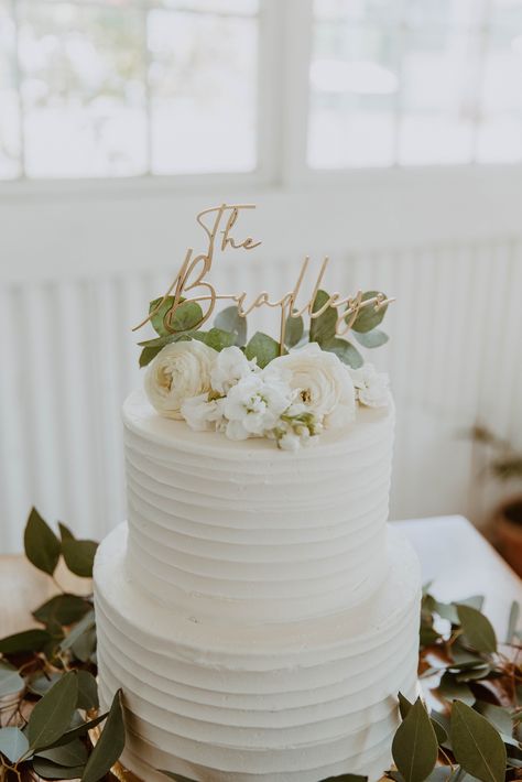 White wedding cake with greenery and white florals decorating the cake with a gold wedding topper of the bride and groom’s last name on top of the cake at the White Shanty venue in Provo Utah. Dream Wedding Cake, Gray Wedding, White Wedding Cakes, Simple Wedding Cake, White Wedding Cake, Wedding Cakes With Flowers, Elegant Wedding Cakes, Wedding Cake Inspiration, Tiered Wedding Cake