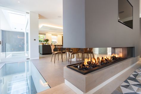 This stunning three sided gas fireplace forms part of a room divider. Three Side Fireplace, Three Sided Fireplace Ideas Modern, 2 Sided Fireplace Living Room Modern, Three Way Fireplace, Media Wall Room Divider, 2 Sided Gas Fireplace, Fire Room Divider, Modern Two Sided Fireplace, Room Divider Fireplace