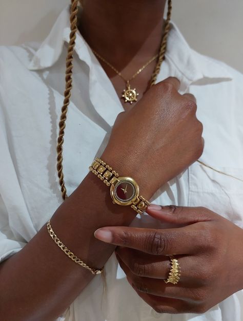 Picture of a black girl wearing different types of gold jewelry (gold bracelet, gold ring, gold watch and gold necklace). She is posing with her hands crossed over a crisp white shirt. Jewelry Inspo Black Women, Gold Bracelet For Women Aesthetic, Dark Skin Jewelry, Jewelry Accessories Black Women, Beige Aesthetic Black Woman, Gold Bracelet Stack Black Woman, Jewellery On Black Women, Black Woman Accessories, Stacked Rings Black Women