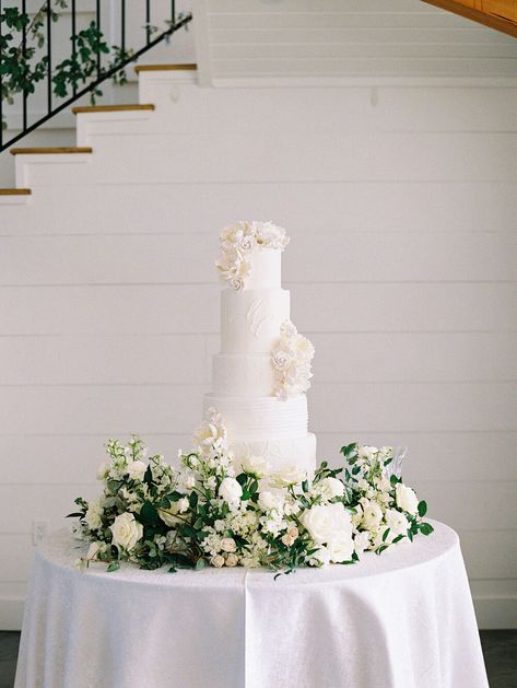 Wedding Cake White Flowers Greenery, Wedding Cake Table With Flowers, Cake Table Designs Wedding Reception, Wedding Cake Flower Arrangement, Wedding Cake Table Floral Arrangements, Flowers Around Wedding Cake Table, Cake Table Wedding Elegant, Wedding Cake With Flowers Around Base, White Flowers Wedding Cake