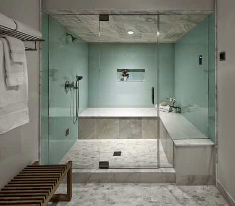 An unused dark room became a well-used space with a stunning steam shower to help with the aches and pains after working out in the home Pilate’s area just outside the changing room.  The light green porcelain wall tiles have the look of glass but without their fragile nature.  The Calcutta marble on the shower bench, ceiling and floors add warmth and style. Bathroom With Changing Room, Glass Enclosed Showers, Shower Bed, Shower Ceiling, Steam Room Shower, Sauna A Vapor, Calcutta Marble, Master Bath Shower, Sauna Steam Room