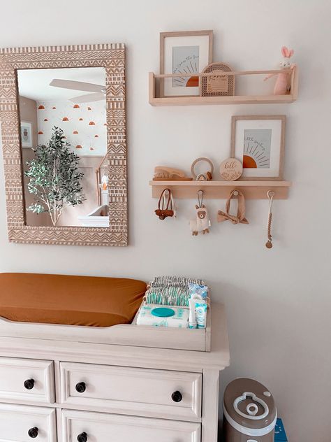 Beige and rust baby girl nursery with peg shelves and changing table Wall Decor Over Changing Table, Changing Area Nursery, Nursery Shelves Above Changing Table, Boho Nursery Changing Tables, Shelf Above Changing Table, Mirror Over Changing Table, Girl Nursery Changing Table, Changing Table Wall Decor, Above Changing Table Decor