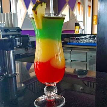 Best Beach Drinks to Order at All-Inclusive Resorts (with Recipes!) | Savored Journeys •  Bob Marley  Bottom layer: Blend 1 oz. rum, 2 oz. strawberry daiquiri mix and 1 cup ice  Middle layer: Blend 1 oz. rum, ½ oz. orange curacao, 3 oz. mango, 1 ½ oz. sweet & sour mix and 1 cup ice. Reserve some for top layer.  Top layer: add ½ oz. blue curacao to remaining orange mixture Bob Marley Drink Recipe How To Make, Bob Marley Cocktail, Best Beach Drinks, Bob Marley Drink, Jamaican Drinks, Alcoholic Recipes, 43rd Birthday, Pool Drinks, Frozen Drink