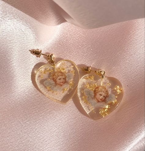 our gorgeous cherub resin gold flake earrings with a golden stud! aesthetic earrings that glimmer in the sun. available 1/20. Website link will be added soon! Resin Earrings Aesthetic, Resin Aesthetic Ideas, Aesthetic Resin Jewelry, Resin Jewelry Aesthetic, Aesthetic Resin Art, Cherub Earrings, Stud Aesthetic, Resin Aesthetic, Aesthetic Earring