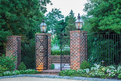 Brick pillars adorned with wrought-iron fencing create a stately side entry. Brick Pillars, Estate Gardens, Fountain Garden, Brick Columns, Fence Plants, Cedar Garden, Driveway Entrance, Living Fence, Brick Fence