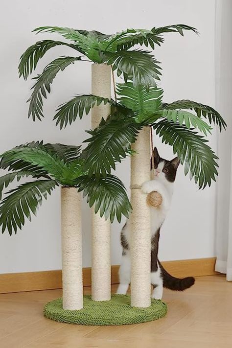 Kitten holding on to the dangling ball from a palm tree-shaped cat scratcher with three poles, each one topped with green leaves to simulate palm trees. The scratcher has a fake grass base. Mushroom Scratching Post, Kitten Scratching Post, Black Cat Scratching Post, Mushroom Cat Scratching Post, Cute Scratching Post, Cat Scratcher Tree, Jungle Oasis, Cat Hacks, Pet Projects