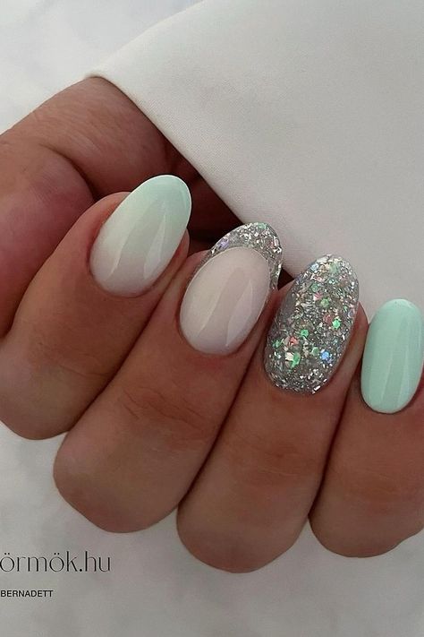 Elevate your style with these almond-shaped nails showcasing a chic blend of pastel and sparkle. Two nails dazzle with a dense silver glitter overlay, capturing light and attention, while the remaining complement with a soft mint green and subtle ombré transition to opaque white, exuding a fresh, serene vibe. Perfect for adding a splash of spring elegance to any look. 💅✨  // Photo Credit: Instagram @_bettynails_ Mint Green Glitter Nails, Mint Green And Silver Nails, Mint Green Christmas Nails, Mint Christmas Nails, Mint Green And White Nails, Pastel Mint Nails, Green And Glitter Nails, Light Green Nail Ideas, Glitter Green Nails