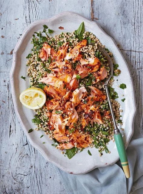 Roast Harissa Salmon with Lemony Giant Couscous from The Great British Bake Off: Winter Kitchen cookbook. Salmon is an oily fish that is packed with flavour, which makes it a great choice for partnering the chilli kick of harissa. Rose harissa has a more fragrant flavour than regular harissa but either would work well here. The beads of giant couscous absorb their lemony dressing, making them little flavour bombs. Lemony Couscous, Harissa Salmon, Giant Couscous, Winter Kitchen, Quit Sugar, Salmon Dishes, Baked Salmon, Fish Dishes, Delicious Dinner