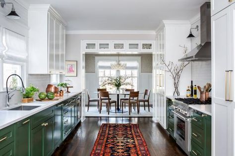 This galley kitchen is warm and inviting thanks to green cabinets, brass pulls, hardwood floors and a bright orange runner. Custom doors help conceal the owners' appliances, so they don't detract from the earthy aesthetic, while wood-themed wallpaper carries the design into the dining area. Two Toned Kitchen Cabinets, Galley Kitchen Remodel Ideas, Galley Kitchen Layout, Kitchen Cabinet Color Ideas, Galley Kitchen Design, Kitchen Design Styles, Galley Kitchen Remodel, Galley Style Kitchen, Galley Kitchens