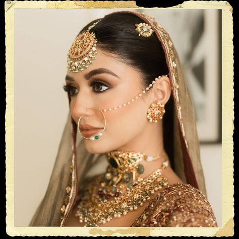 The intricate maang tikka, with its detailed gold work and delicate hanging pearls, graces her forehead, perfectly complemented by the large, ornate nath (nose ring) that adds a classic touch of elegance. Her neck is beautifully accentuated by a layered choker necklace, encrusted with a blend of precious stones and elaborate filigree designs, epitomizing luxury and grandeur. The look is completed with statement earrings, an opulent ring, and a pair of intricately designed bangles, all contrib... Nath Nose Ring, Bridal Nose Ring, Bridal Lehenga Designs, Choker Necklace Designs, Layered Choker Necklace, Maang Tikka, Nose Jewelry, Gold Work, Lehenga Designs