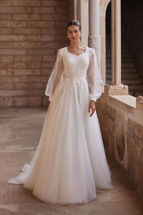 Step into a fairytale with Moonlight Bridal's M5086 gown, a stunning embodiment of romance and modesty. Crafted with delicate tulle, this A-line silhouette flows gracefully, while long illusion bishop sleeves add a touch of ethereal charm. Perfect for the bride seeking timeless elegance on her special day. #tulleweddingdress #modestweddinggown #modestdress Wedding Dresses With Bishop Sleeves, Bishop Sleeves Wedding Dress, Elegant Wedding Dress With Lantern Sleeves, Bishop Sleeve Wedding Dress, Wedding Core, Modest Long Sleeve Wedding Dresses, Lace Bodice Wedding Dress, Moonlight Bridal, Modest Bride