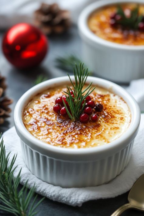 Creme brulee topped with red berries and a sprig of rosemary, surrounded by holiday decorations. Holiday Creme Brulee, Christmas Dessert Elegant, Eggnog Creme Brulee, Eggnog Desserts Christmas, Flavored Creme Brulee, Christmas Creme Brulee, Christmas Panna Cotta, Christmas Dessert Aesthetic, Christmas Dessert Ideas Fancy