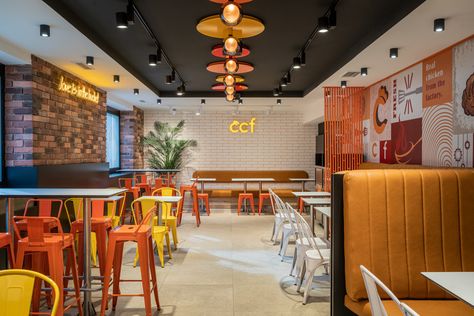 Upstairs guest area with colorful metal chairs, tile with colored edges, led brand logo, and interior plant. Crispy Chicken Factory by miaza design studio in vienna finished in 2023 Vietnamese Interior Design, Vietnamese Interior, Grill House, Design Studio Interior, Fast Chicken Recipes, Small Restaurant Design, Furniture Concept, Chicken Restaurant, Small Restaurant