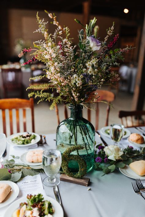 These tables at a Johnson's Locust Hall Farm fall wedding were just amazing. The moss covered table numbers along with the green glass for vases are stunning! Wildflower Wedding Centerpiece | Rustic Wedding Centerpieces | Wedding Table Decorations Green Glass Wedding Centerpieces, Cottage Core Table Centerpiece, Green Vase Wedding Centerpiece, Wedding Glass Vase Centerpieces, Centerpieces Wedding Wildflowers, Rustic Vases Centerpieces, Cottage Wedding Centerpieces, Green Glass Wedding Decor, August Wedding Table Centerpieces