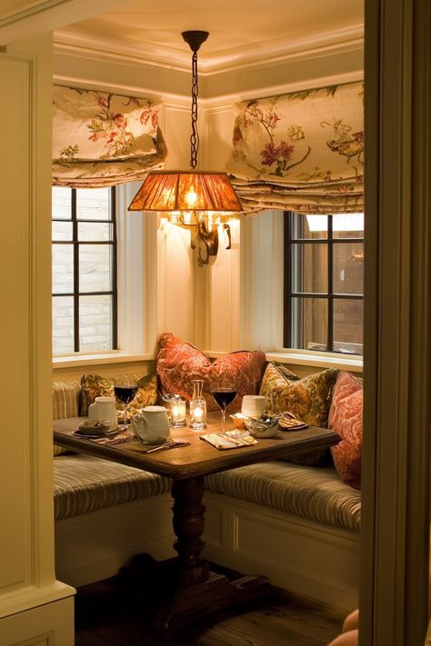 Cozy restaurant nook with a wooden table set for two, featuring floral curtains and a warm, hanging light fixture. Dining Alcove Kitchen Nook, Breakfast Nook Booth Seating, Library Breakfast Nook, Corner Window Nook, Wallpaper Kitchen Nook, Dining Room Reading Nook, Kitchen Nook Ideas Small Corner, French Breakfast Nook, Reading Nook In Kitchen