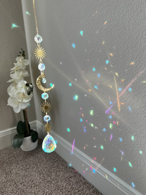 Beautiful celestial sun catcher made with premium materials like 18k gold plated chain, raw brass sun components, aurora borealis crystals and a large 50mm teardrop AB crystal. Length is approximately 14mm Suncatchets/ light catchers are a great way to let someone know that they are your sunshine ✨ What better gift than rainbows and sparkles?! Sun Catcher Bedroom, Sun Catcher Crystal, Dream Catcher Crystals, Light Catchers Diy, Sun Catchers Diy How To Make, Spiritual Room Ideas, Dream Catcher Light, Celestial Room Decor, Sun Catchers Diy