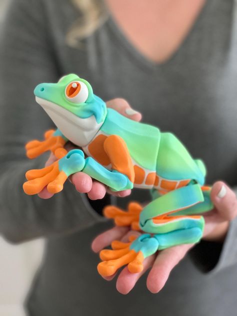 This Custom 3D Printed Articulated Frog fidget spinner toy comes in multiple sizes and several beautiful colors! Our enchanting and functional decor piece adds a touch of fantasy to any space and makes a wonderful and unique present. Made with eco-friendly materials (biodegradable filaments), this beautiful dragon makes an ideal gift for all ages, from dragon enthusiasts to bookworms looking to add a little fantasy to their surroundings. 📸 Model #1 Details:        Large Adult (no spots) Useful 3d Prints Products, Frog Themed Gifts, Cool Kids Toys, Figets Toys, Fidget Toys 3d Printer, Frog Family, Frog Toy, 3d Printing Toys, 3d Printed Dragon Fidget