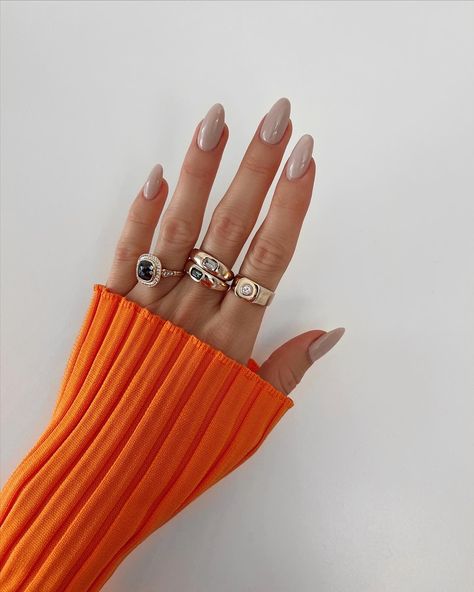 Hand with grey beige nails and gold rings wearing an orange top Ttpd Inspired Nails, Greige Nails, Nails Minimalistic, Fall Nail Idea, Perfect Nail Color, Fall Almond Nails, Nail Designs For Fall, Purple Chrome Nails, Classy Fall Nails