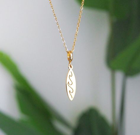 ༄ Catch the perfect wave with this minimalistic 𝗚𝗼𝗹𝗱 𝗦𝘂𝗿𝗳𝗯𝗼𝗮𝗿𝗱 𝗡𝗲𝗰𝗸𝗹𝗮𝗰𝗲. 🌊 🏄 Featuring a beautiful surfboard pendant with a detailed wave engraving. Made with high quality 14k gold plated stainless steel, built to be as long-lasting as your love for the ocean. This necklace is perfect for beach lovers and surfers at heart. ▼ 14k gold plated stainless steel ▼ Length: 45 cm with extend option to 50 cm. ▼ Pendant is approx. 1.5 cm . #surfgirl #beachgirl #surf #surfgirls #surfnecklace #... Surfer Girl Jewelry, Surfboard Necklace, Surf Necklace, Surf Jewelry, Girl Jewelry, Surfer Girl, Beach Lovers, Beach Girl, Surfboard