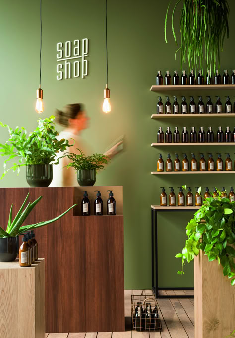 Green Spa Interior Design, Green Retail Interior, Green Retail Design, Green Store Aesthetic, Earthy Retail Design, Accent Wall Retail Store, Green Spa Room Ideas, Green Store Design, Retail Area In Salon