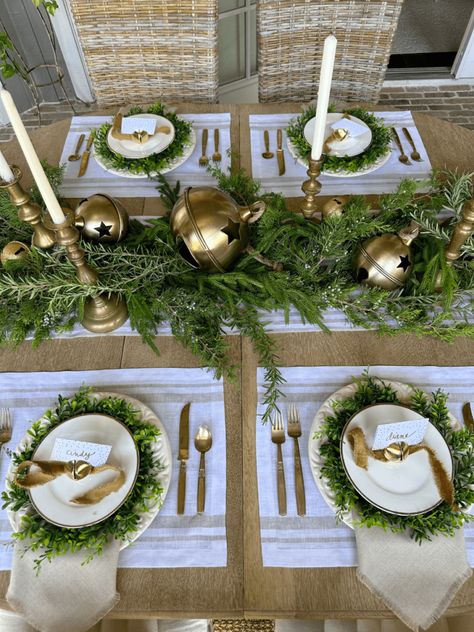 This simple Christmas tablescape with gold bells and greenery is classic and beautiful. It was so easy to put together and the fresh greenery adds a natural touch and smells amazing. Your holiday tablescapes don't have to take a lot of time and you don't have to spend a lot of money to create a beautiful table. This Christmas tablescape, centerpiece and place settings are perfect for any holiday get together including your Christmas dinner. Formal Christmas Party Table Centerpieces, Dining Table Holiday Decor, Round Tablescapes Christmas, Round Dining Table Christmas Decor Centerpiece, Green Christmas Centerpieces, Easy Christmas Table Decor, Holiday Place Settings Christmas, Christmas Centerpieces For Round Tables, Elegant Christmas Tablescapes