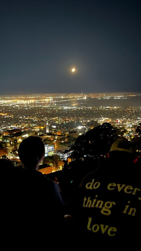 Two people are looking at the beautiful view of San Francisco. It is night so the lights are bright and the sky is clear. The back of the boy’s sweater on the right reads “do everything in love.” Citylights Night Aesthetic, Night Hike Aesthetic, Night Hike, Night City View, Night View Aesthetic, Quiet Photos Night, Night View, City Lights Aesthetic, Miguel Diaz