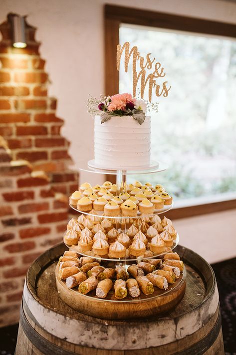 Can't decide which dessert to serve at your wedding? Why not have them all?! This gorgeous wedding cake has a base of sweet cannolis, cupcakes and choc chip muffins, topped with a simple yet beautiful single-tier wedding cake. One Tier Cake With Cupcakes, Single Tier Wedding Cake Display, Small Wedding Cake And Cupcakes, Single Tier Wedding Cakes, Alternative Wedding Cake Ideas, Angelina Cafe, Single Tier Wedding Cake, Cannoli Cupcake, Choc Chip Muffins