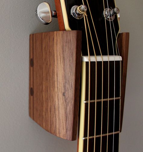 I made these guitar hangers out of black walnut.  It’s a pretty simple DIY project easily completed in one weekend. These guitar hangers are designed for my son’s Yamaha acoustic guitars but the measurements could easily be adjusted to fit most guitars simply by changing the width of the back piece. This is one of those projects where it’s good … Guitar Holder Wall Diy, Guitar Hanger Diy, Diy Guitar Stand, Guitar Hangers, Guitar Display Case, Weekend Woodworking Projects, Guitar Holder, Guitar Storage, Guitar Wall Hanger