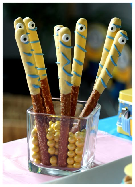 "Minion Chocolate Pretzel Rods" standing in a square jar from Dollar tree filled with yellow Sixlets. Minions Treat Table, Minion Themed Desserts, Minion Themed Snacks, Minion Birthday Treats, Minion Charcuterie Board, Minion Rice Krispie Treats, Minion Birthday Party Food, Minion Food Ideas, Minion Pretzels