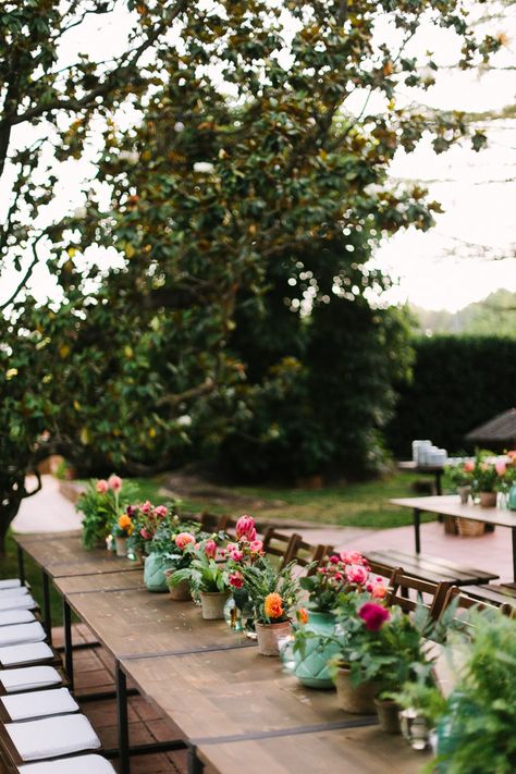 Outdoor Reception Plant Pot Wedding Flowers - Diez & Bordons Photography | Outdoor Destination Spanish Wedding at Masía Ribas | Rustic Trestle Tables with Vibrant Plant Pot Decor | Xavier González Wedding Dress Potted Plant Centerpieces, Retreat Food, Plant Pot Decor, Flower Pot Centerpiece, Wedding Ideas 2024, Plant Centerpieces, Vintage Wedding Ideas, Flower Table Decorations, Trestle Tables