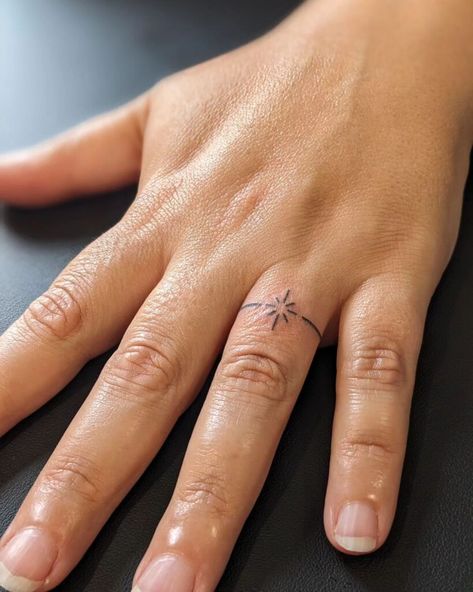 24 Unconventional Wedding Ring Ideas To Ink On Your Finger And Redefine Eternal Love White Ring Finger Tattoo, Minimalist Ring Tattoo, Unique Wedding Ring Tattoos, Ring Tattoo Wedding, Marriage Tattoos Ring Finger Initial, Roman Numeral Finger Tattoo, Simple Ring Tattoo, Womens Ring Tattoo, Dainty Ring Tattoos For Women