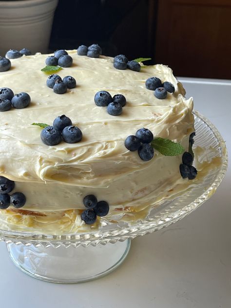 a photo of a round yellow cake with whipped buttercream icing garnished with blueberries and mint on a glass cake stand Lemon Blueberry Cake Aesthetic, Cake Blueberry Decoration, Pretty Cakes Simple, Lemon And Blueberry Cake Decoration, White Cake With Blueberries, Homemade Birthday Cake For Boyfriend, Blueberry Cake Aesthetic, Homemade Birthday Cake Decorating, January Birthday Cake