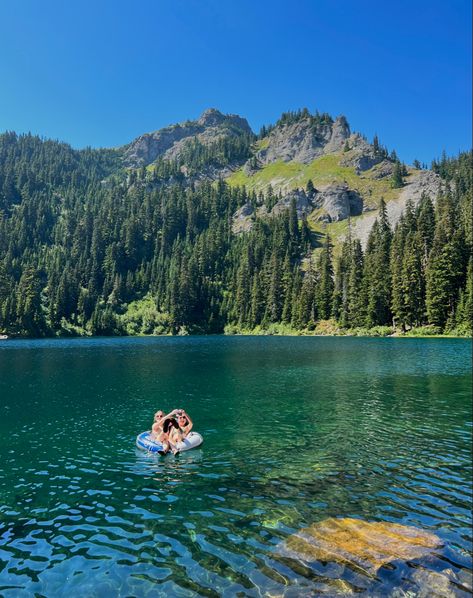 Two girls floating with an inner tube on an alpine lake. There are mountains in the background and it is a sunny day. Pacific Northwest Hikes, Lake Days Aesthetic, Mountains With Lake, Pacific Northwest Aesthetic, Pacific Northwest Hiking, Pacific Northwest Summer, Joy Aesthetic, Sunnyvale California, Lake Swimming