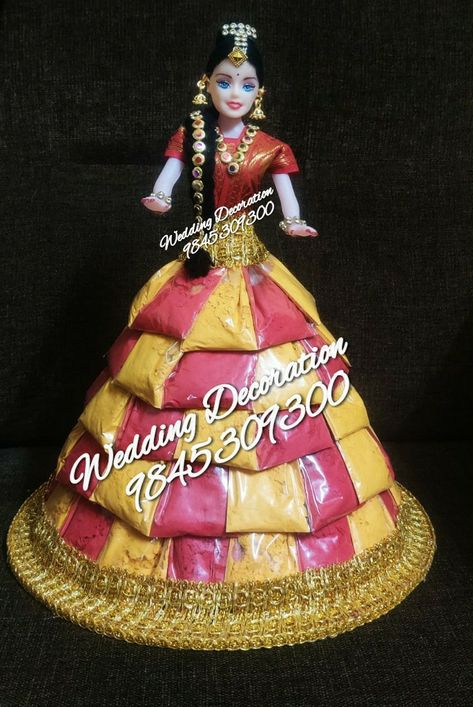 Using Haldi Kumkum packets, this doll is designed. Call 9845309300 to place orders Chocolate Doll Decoration Ideas, Chocolate Doll Decoration, Haldi Kumkum Packing Ideas, Ratha Saptami, Chocolate Doll, Barbie Decorations, Haldi Kumkum, Doll Fancy Dress, Baby Cast