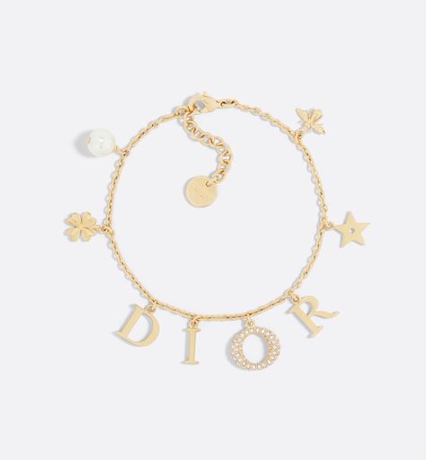 The Dio(r)evolution bracelet is a creation with a modern aesthetic. The Dior letters are suspended from a gold-finish metal chain, while the pavé of silver-tone crystals adorning the letter O adds a luminous touch. The design is embellished with a white resin pearl and signature Dior symbols, including stars, the clover and the bee. The sophisticated bracelet can be combined with other creations from the Dio(r)evolution line. Dior Charm Bracelet, Dior Armband, Dior Bracelet Gold, Bracelet Dior, Dior Jewellery, Dior Bracelet, Bracelets Luxury, Resin Pearl, Dior Necklace