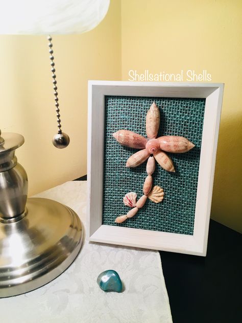 Brand new creation... Blooming Olives 🐚 This cute olive shells flower design is looking for a new home...the frame can stand alone or be hanged on a wall. PM me for details if interested. Frame Dimensions: 6”W x 8”H Shells: Lettered Olives and Kitten’s Paws Background: Aqua Burlap Olive Shells Crafts, Olive Shell Art, Olive Shell Crafts Seashells, Lettered Olive Shell Crafts, Olive Seashell Crafts, Olive Shell Crafts, Lettered Olive Shell, Shell Frames Diy Seashell Crafts, Sea Shell Frames Diy