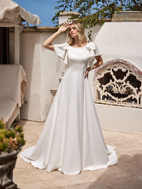 Embrace timeless elegance on your wedding day with our exquisite modest crepe wedding dress, designed to capture hearts with its classic beauty and thoughtful details. Crafted from luxurious crepe back satin, this gown exudes a graceful sheen that enhances its sophisticated A-line silhouette. Moonlight Modest style M5093 is a wedding dress that features a flattering natural waistline that defines your figure with understated charm. Short flutter sleeves adorned with delicate bows on the ... Conservative Wedding Dress, Simple Bridal Gown, Tiered Wedding Dress, Simple Bridal Gowns, Moonlight Bridal, Mermaid Ball Gown, Modest Bride, Crepe Wedding Dress, Bow Wedding Dress