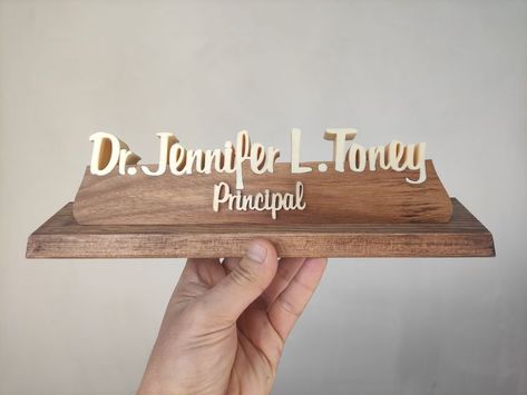 This specially designed table sign is made entirely of natural wood. The table name holder will attract attention with its elegant design. The Personalized Nameplate leaves its peers behind with its natural and decorative appearance. Custom nameplate with your name and title gives your desk a distinctive look. Our products are made of natural wood. In this product, the name parts are made of poplar wood and the pedestal on which the names sit is made of walnut wood. The ground is made of pine Table Name Holders, Natural Wood Desk, Custom Desk Name Plates, Name Holder, Custom Name Sign, Desk Name Plate, Teacher Desk, Custom Desk, Desk Name