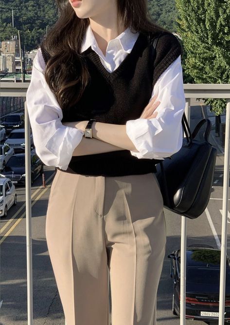 Achieve a timeless and polished look with this classic layered outfit featuring a black knit sweater vest over a crisp white button-down blouse. Paired with tailored beige trousers, casual and sophisticated. Whether for work or a coffee date, this look delivers effortless elegance. Accessorized with a sleek black leather bag and minimalist watch.  #LayeredLook #ClassicOutfit #BusinessCasual #MinimalistFashion #EffortlessChic #OOTD #styleguide Sweater Vest Formal Outfit, T Shirt With Jeans Outfits, Korean Classy Outfits, Korean Work Outfit, Aesthetic Lawyer, Simple Casual Outfits, Casual Work Outfits Women, Lawyer Fashion, Casual College Outfits