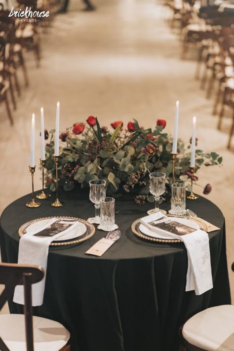 The sweetheart table draped in black, furnished with gold rim charger plates, and decorated with a lovely rose and eucalyptus arrangement. Black And Gold Sweetheart Table, Bride Table Decor, Black Sweetheart Table, Black And White Sweetheart Table, Groom And Bride Table, Red Wine Wedding, Black Tablecloth Wedding, Wedding Groom And Bride, Brides Table Decorations