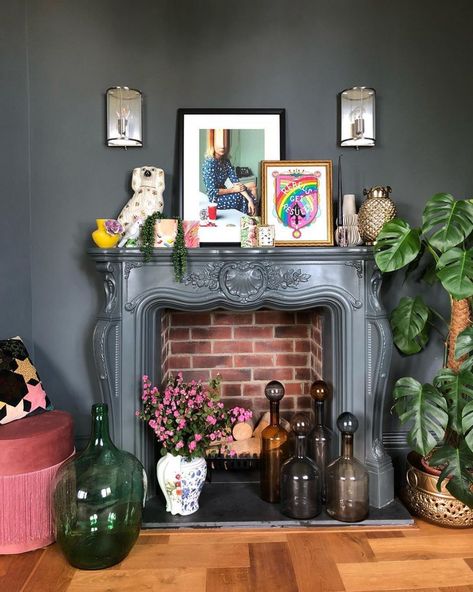 Layer artwork, houseplants and decor for a maximalist look. Quirky Mantle Decor, Mantel Decorating Ideas Maximalist, Maximalist Decor Fireplace, Mantle Decor Maximalist, Maximalist Fireplace Decor, Witchy Mantel Decor, Eclectic Fireplace Mantle Decor, Maximalist Fireplace Mantle, Eclectic Mantel Decor