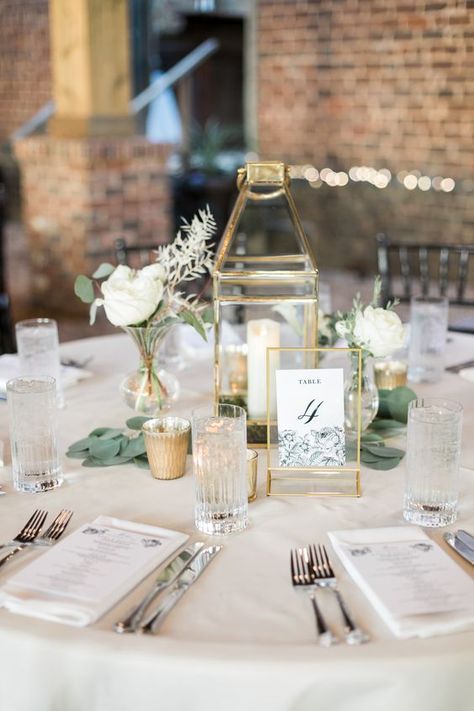 a stylish neutral wedding table with a gold candle lantern, a table number, white blooms and greenery and white linens Gold Wedding Centerpieces, Gold Weddings, Catering Design, Minimalist Wedding Decor, Wedding Table Linens, Wedding Table Number Cards, Elegant Wedding Reception, Floral Wedding Cakes, Wedding Cake Table